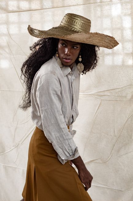 Stylish woman wearing a straw hat and linen shirt exuding a chic fashion statement.