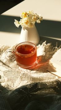Elegant tea setup with daffodils under warm sunlight, creating a cozy atmosphere.