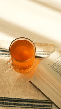 A warm cup of tea next to an open book on a sunlit table, evoking a cozy afternoon feel.