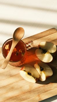 Cozy shot of apple tea and sliced apples on a wooden board, perfect for autumn vibes.