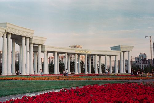 Free Elegant colonnade in Astana Botanical Garden with vibrant flowers and visitors enjoying the summer evening. Stock Photo