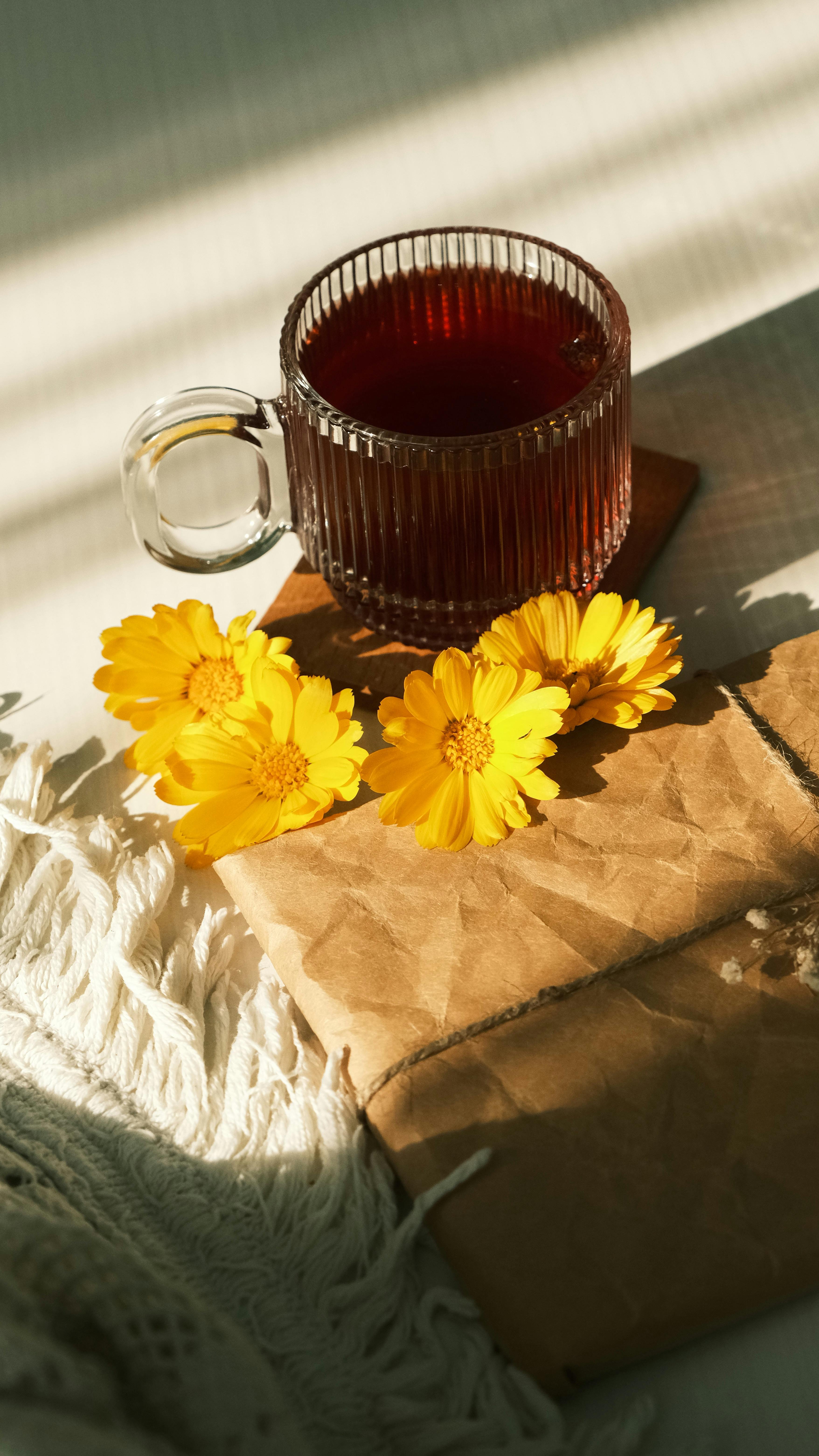 Warm sunlight on tea and flowers creates a cozy and inviting atmosphere.