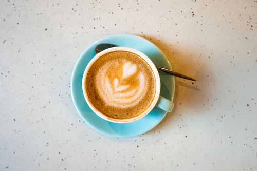Free Top view of a cappuccino with latte art in an aqua blue cup on a speckled countertop in Berlin. Stock Photo