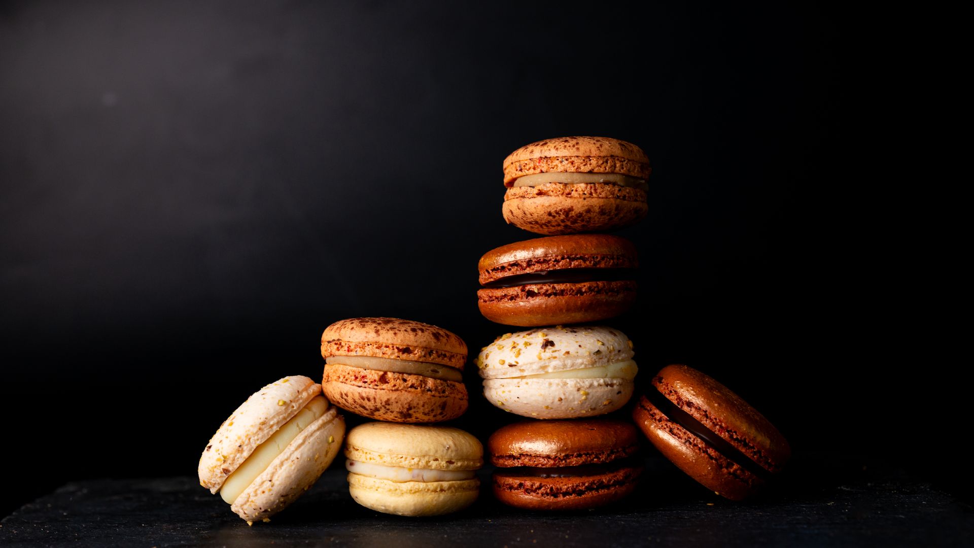 A stack of assorted French macarons set against a dark, luxurious backdrop. Perfect for culinary themes.