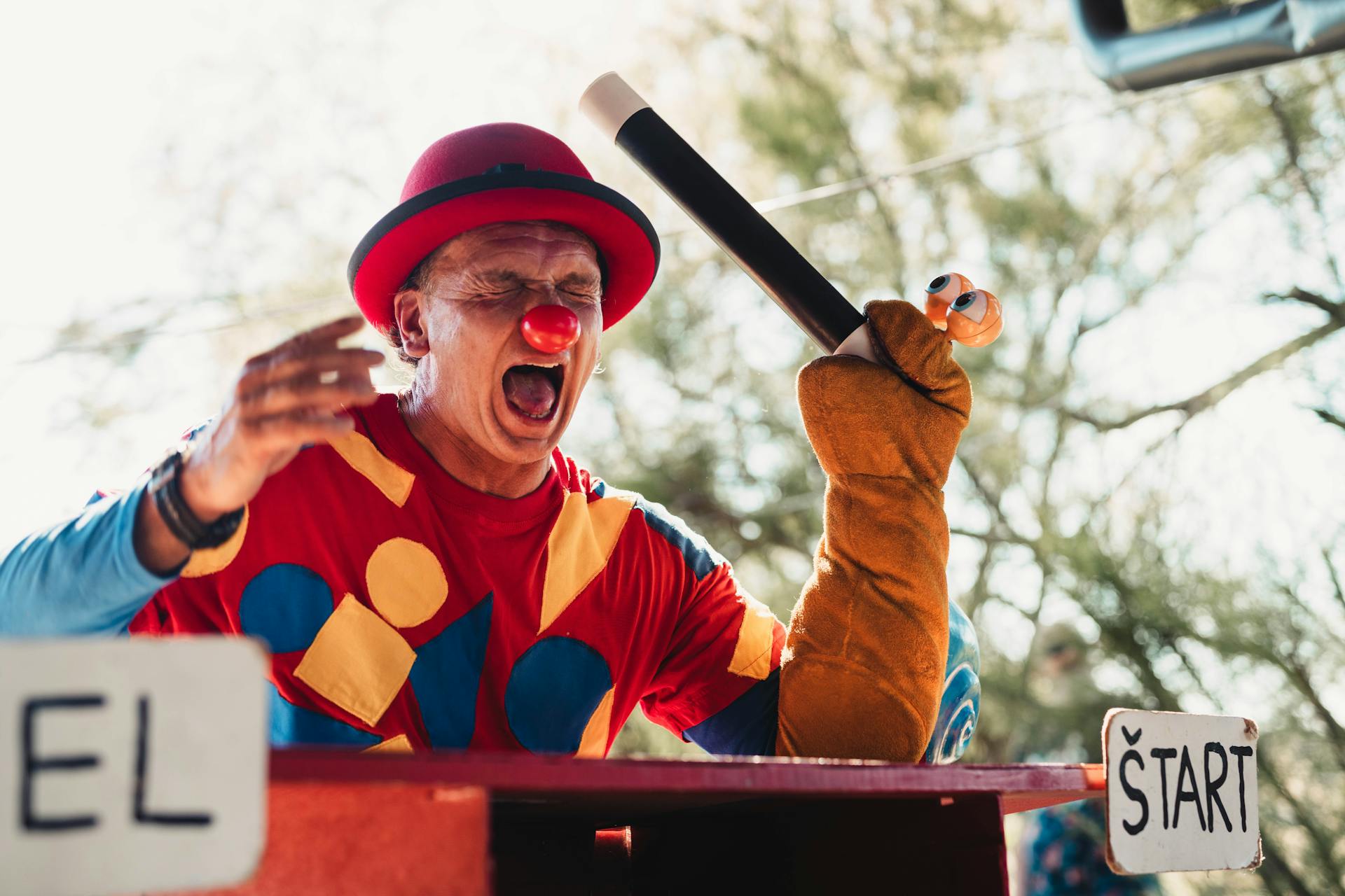 Vibrant clown in colorful outfit entertaining at an outdoor fair.