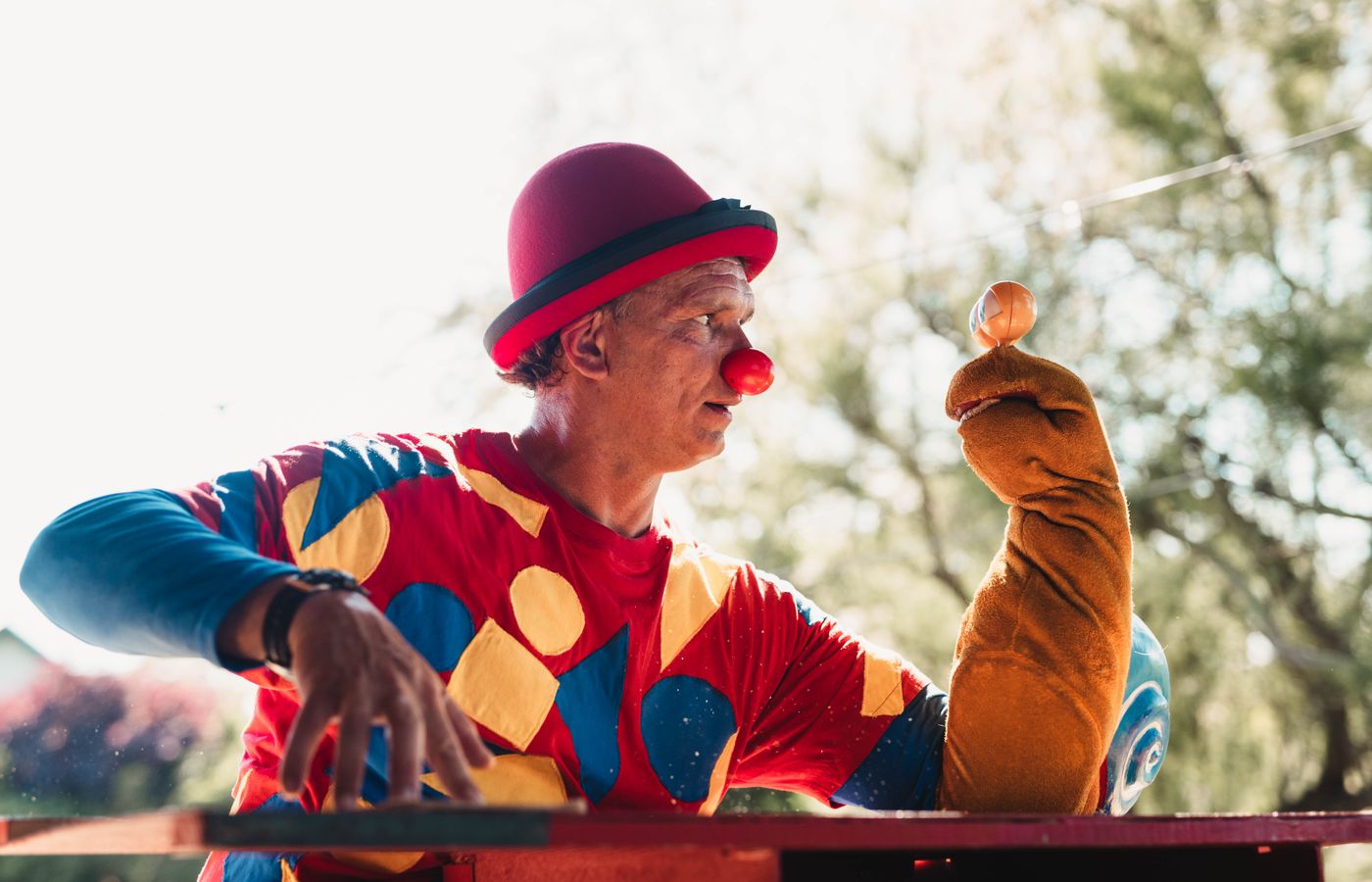 Vibrant clown entertaining with puppet in outdoor setting. Ideal for events and performance themes.