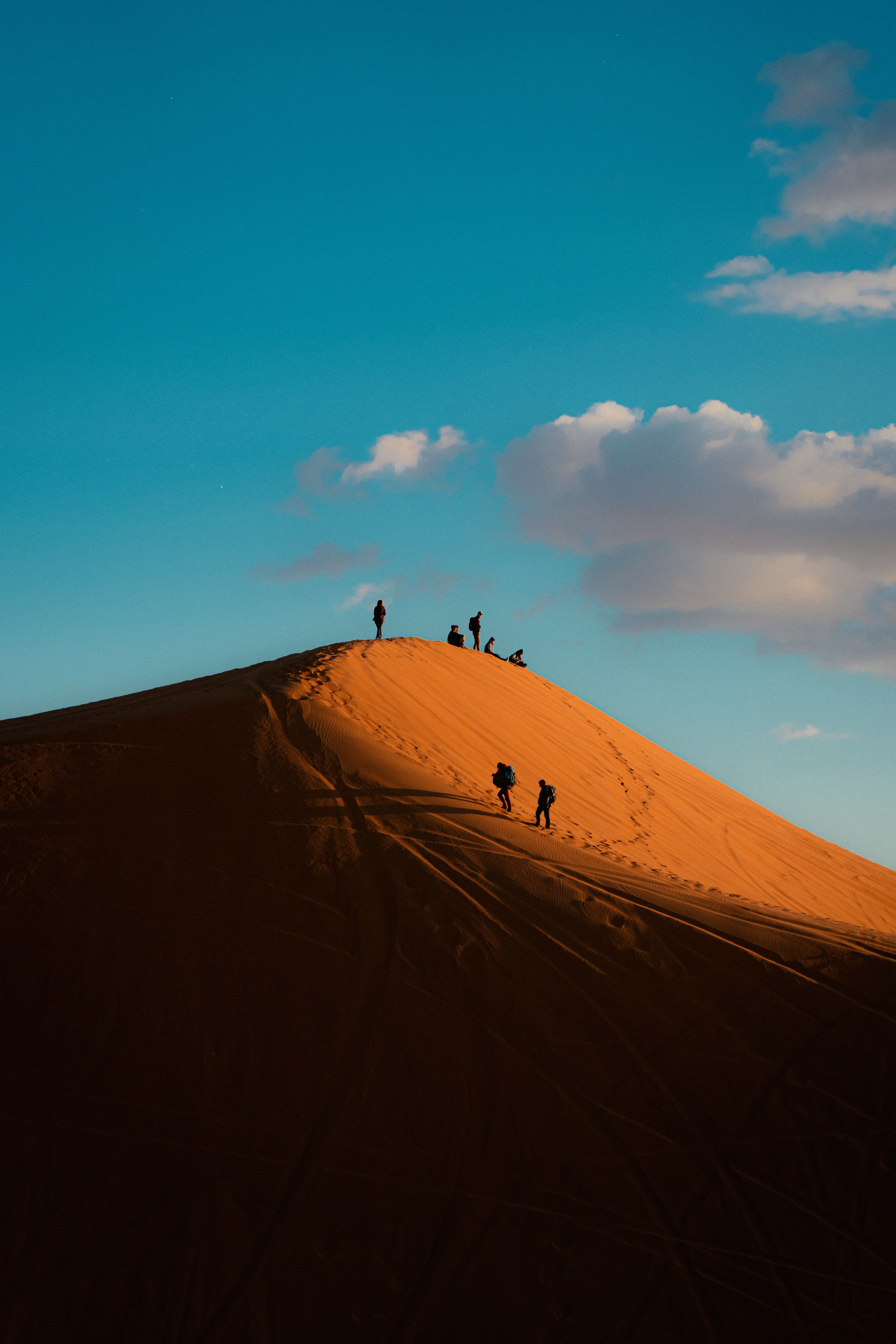 Silhouetted Hikers on Desert Sand Dune · Free Stock Photo