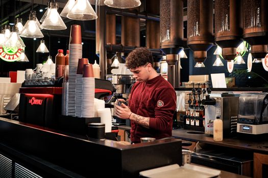 A barista prepares coffee in a modern cafe with stylish interior lighting.