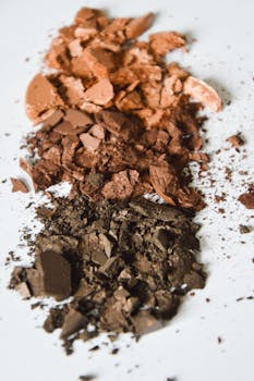 A close-up of crushed makeup powders in brown shades on white surface, artistic display.