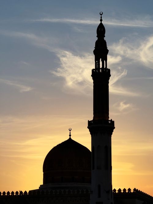 Free Silhouette of a mosque minaret and dome against a vibrant sunset sky in Dubai. Stock Photo