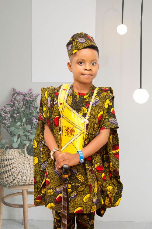Free Boy in vibrant traditional African clothing standing indoors with decorative lights. Stock Photo
