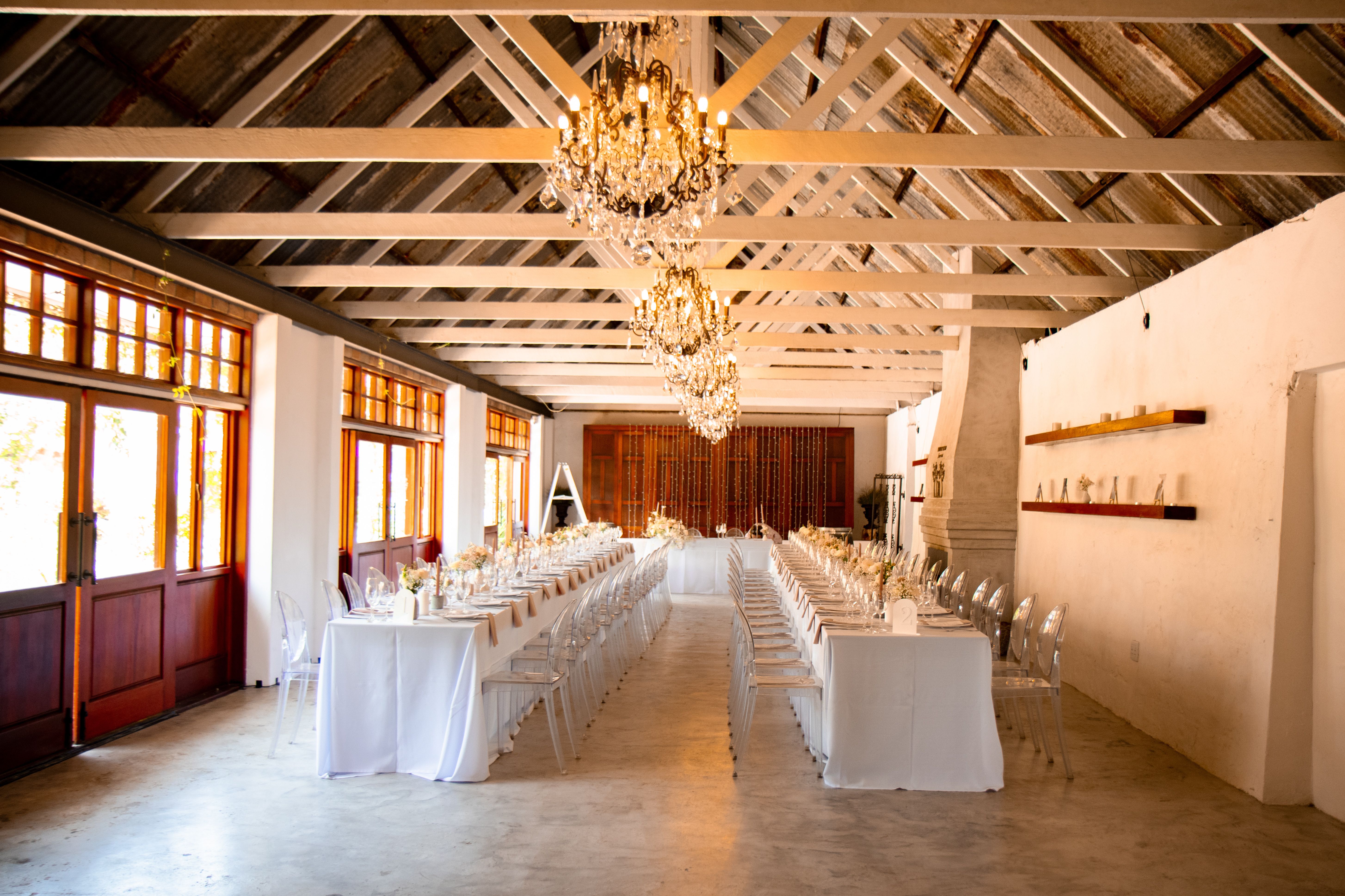 Luxurious wedding venue featuring crystal chandeliers and long dining tables set for an elegant reception.