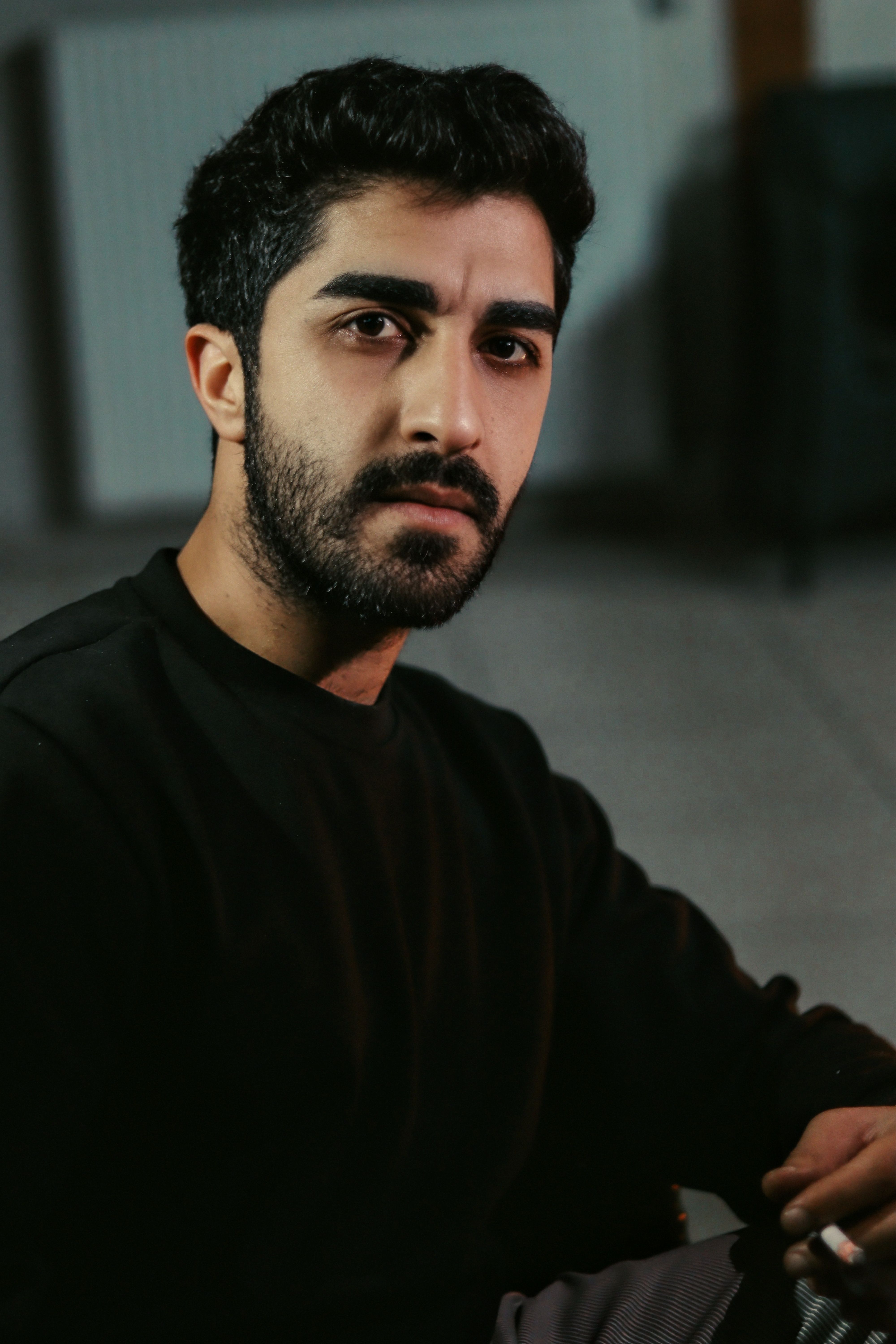 Portrait of a thoughtful young man sitting indoors, exuding a calm and introspective mood.