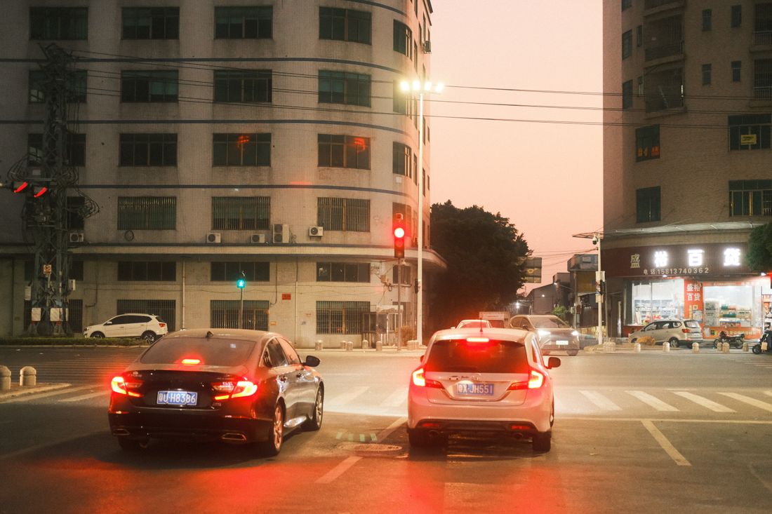 Cars waiting at a city intersection at dusk, highlight urban life