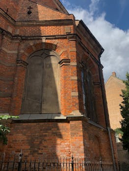 A detailed view of a historic red brick church with Gothic architectural elements, basking in sunlight.