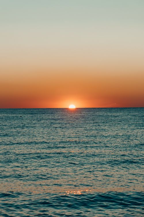 Free Stunning ocean sunset with vibrant hues reflecting on the water. Perfect for serene and calming visuals. Stock Photo