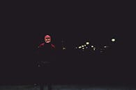 黑暗的街道上，一个戴着发光面具的人独自站立，散发着神秘与阴谋的气息