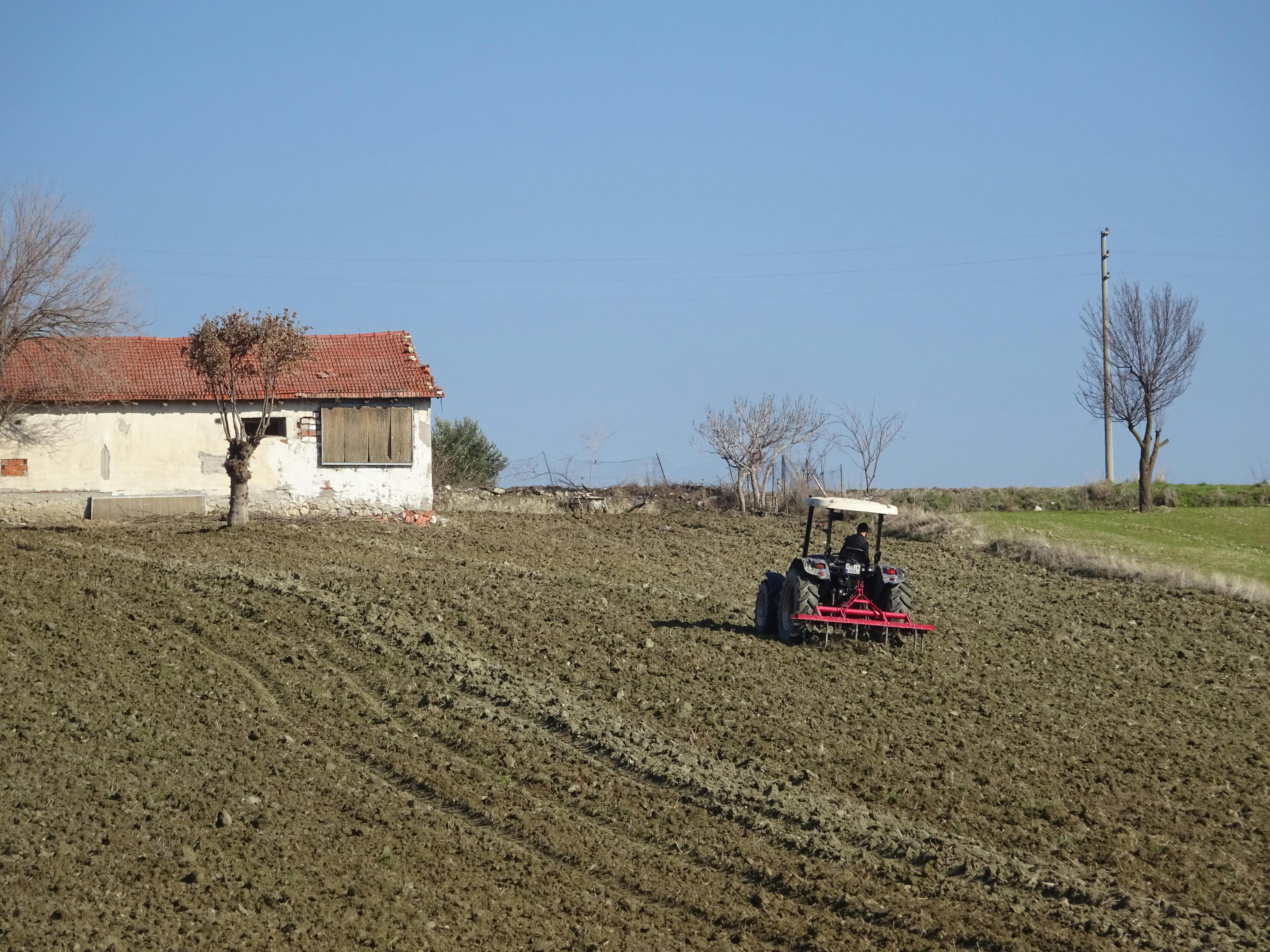 A tractor plowing fields beside an old farmhouse in Selendi, Manisa, Türkiye.