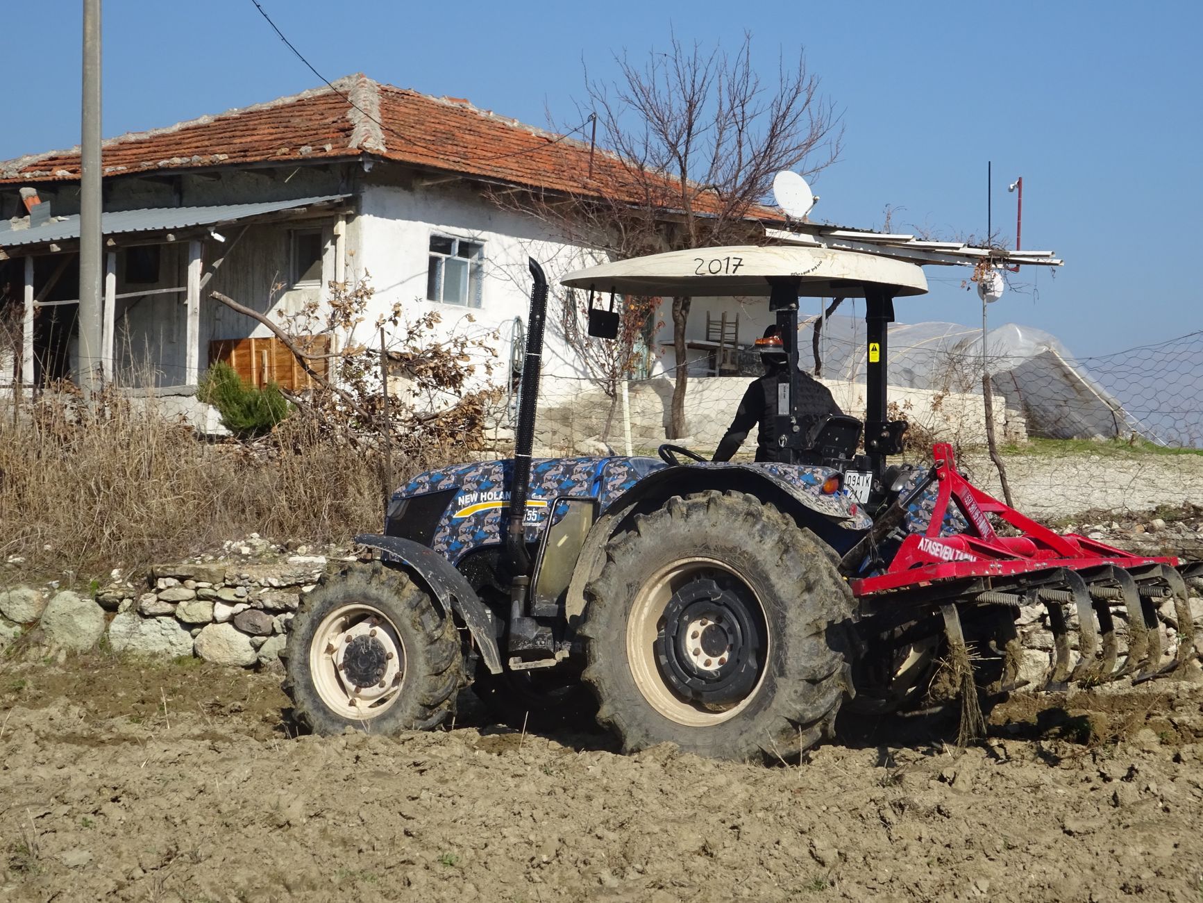 Tractor plowing the field on a sunny day in Selendi, Manisa, capturing rural life.