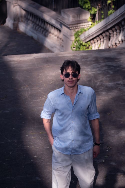 Free Man in sunglasses and blue shirt walking outdoors in Buenos Aires with stylish and natural light ambiance. Stock Photo