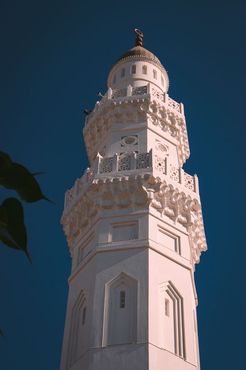 Free A tall, intricately designed minaret stands elegantly against a clear blue sky. Stock Photo