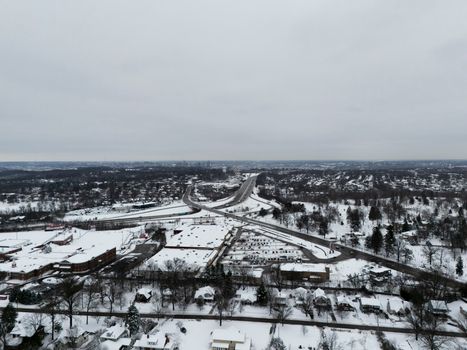 Aerial view of a snow-covered town with a main highway running through it. Winter scene.