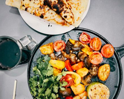 Top view of a colorful grilled vegetable platter with fresh flatbread. Perfect for vibrant food presentations.