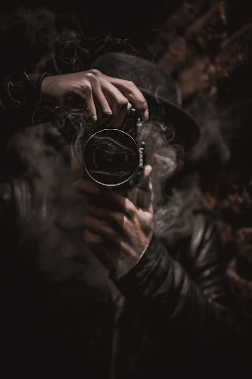 Free Man With Long Silver Gray Hair Wearing Black Jacket Holding A Camera To His Face Stock Photo