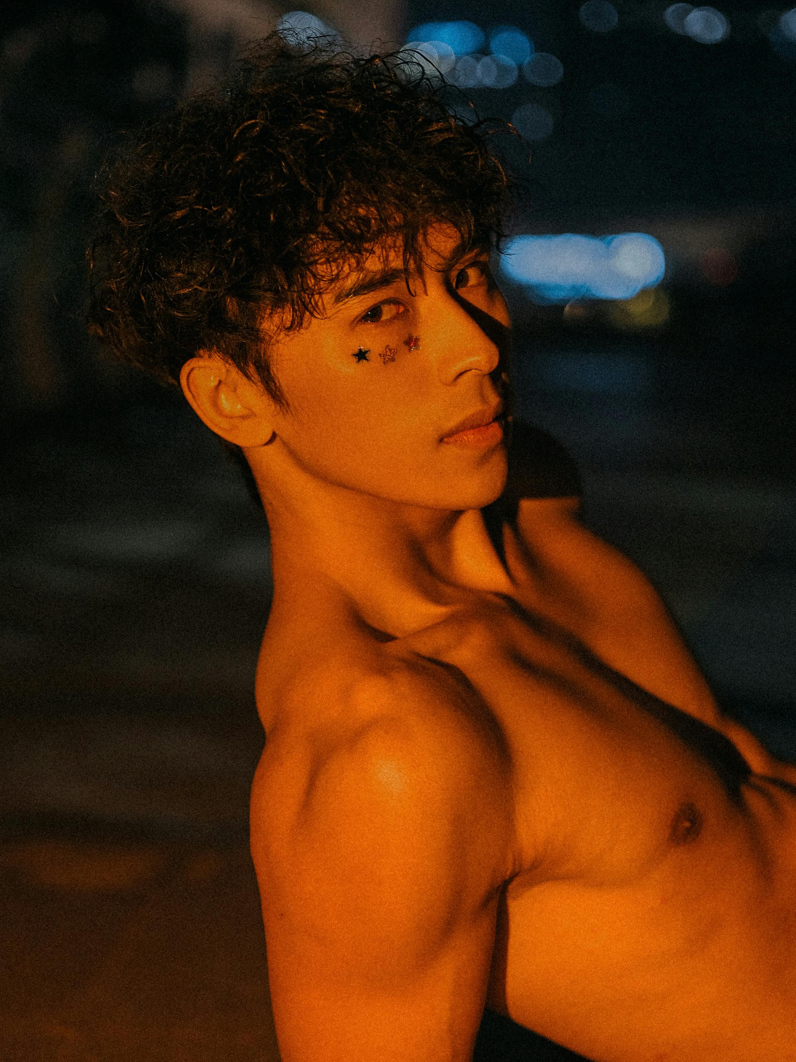 Dramatic nighttime portrait of a young man with star stickers on his face.
