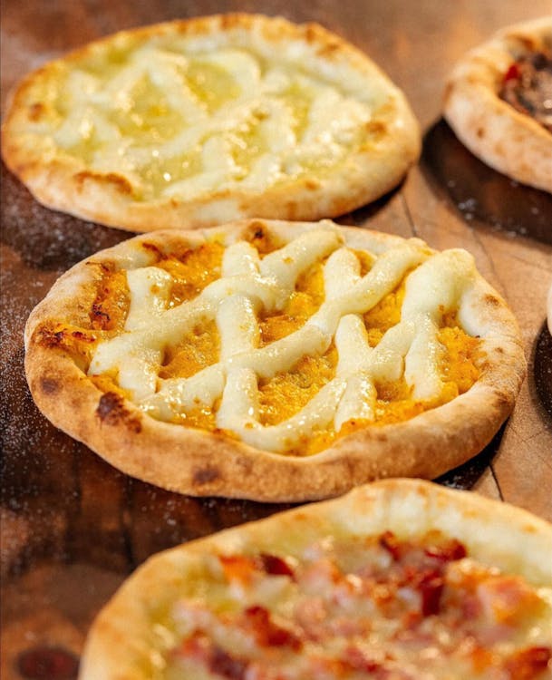 Free Mouth-watering mini pizzas topped with cheese and sauce on a rustic table. Stock Photo