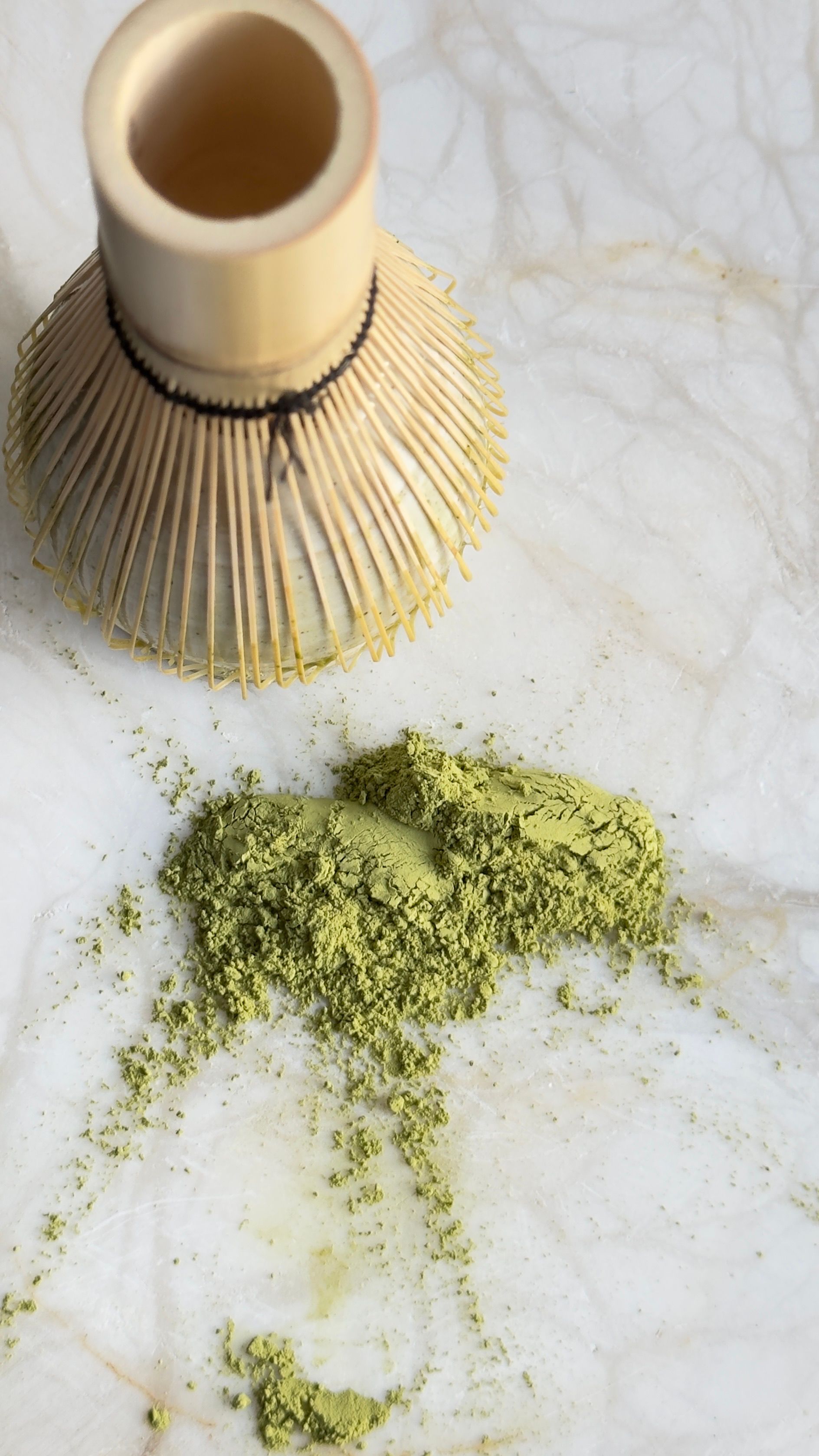 Japanese bamboo whisk with green matcha powder on a marble surface, symbolizing traditional tea preparation. - home gadgets for small spaces