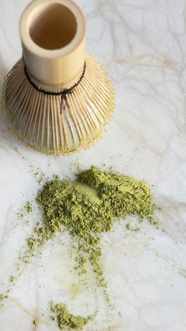 Japanese bamboo whisk with green matcha powder on a marble surface, symbolizing traditional tea preparation. - home gadgets for small spaces