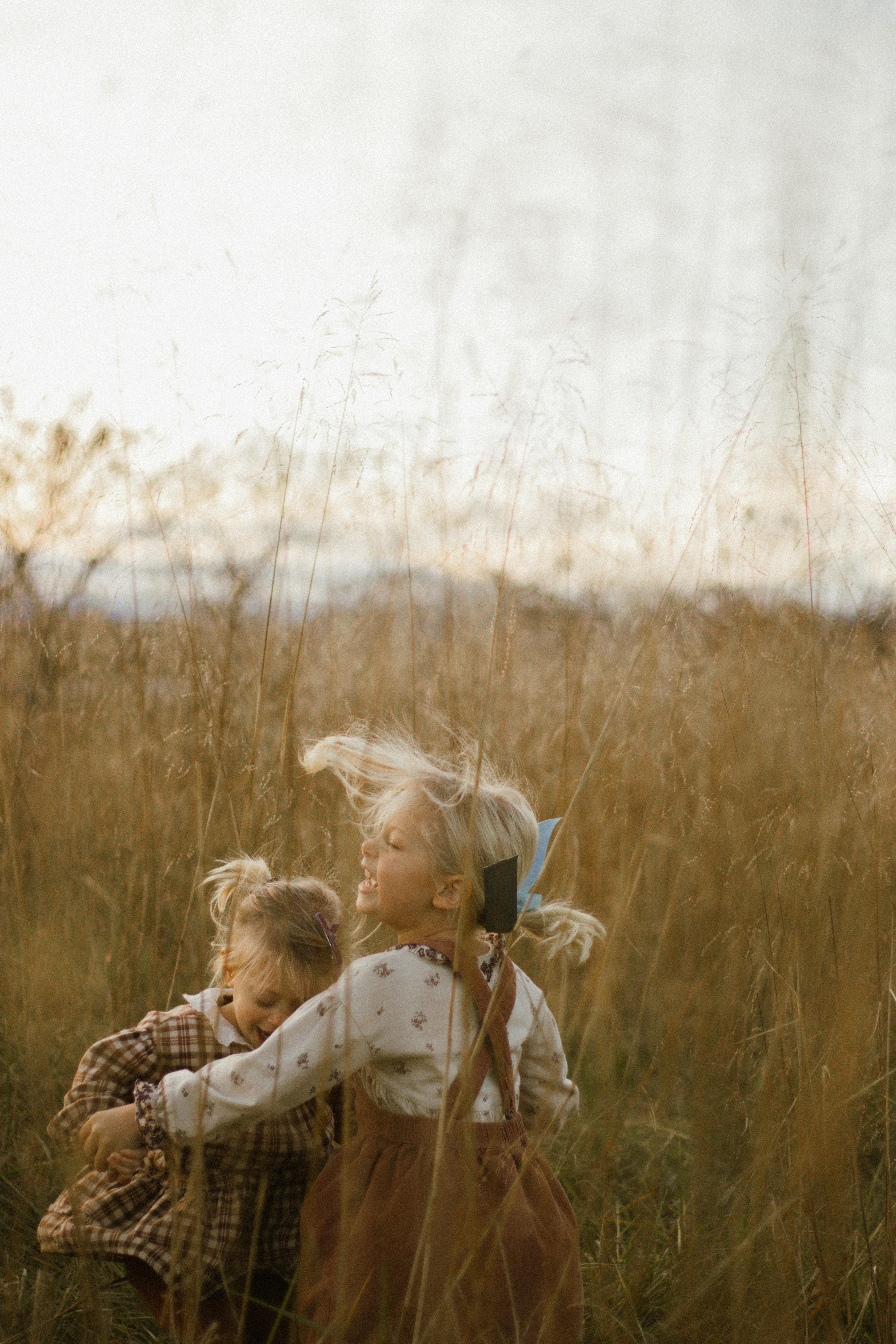 Two young children playing in a sunlit field, capturing candid joy.