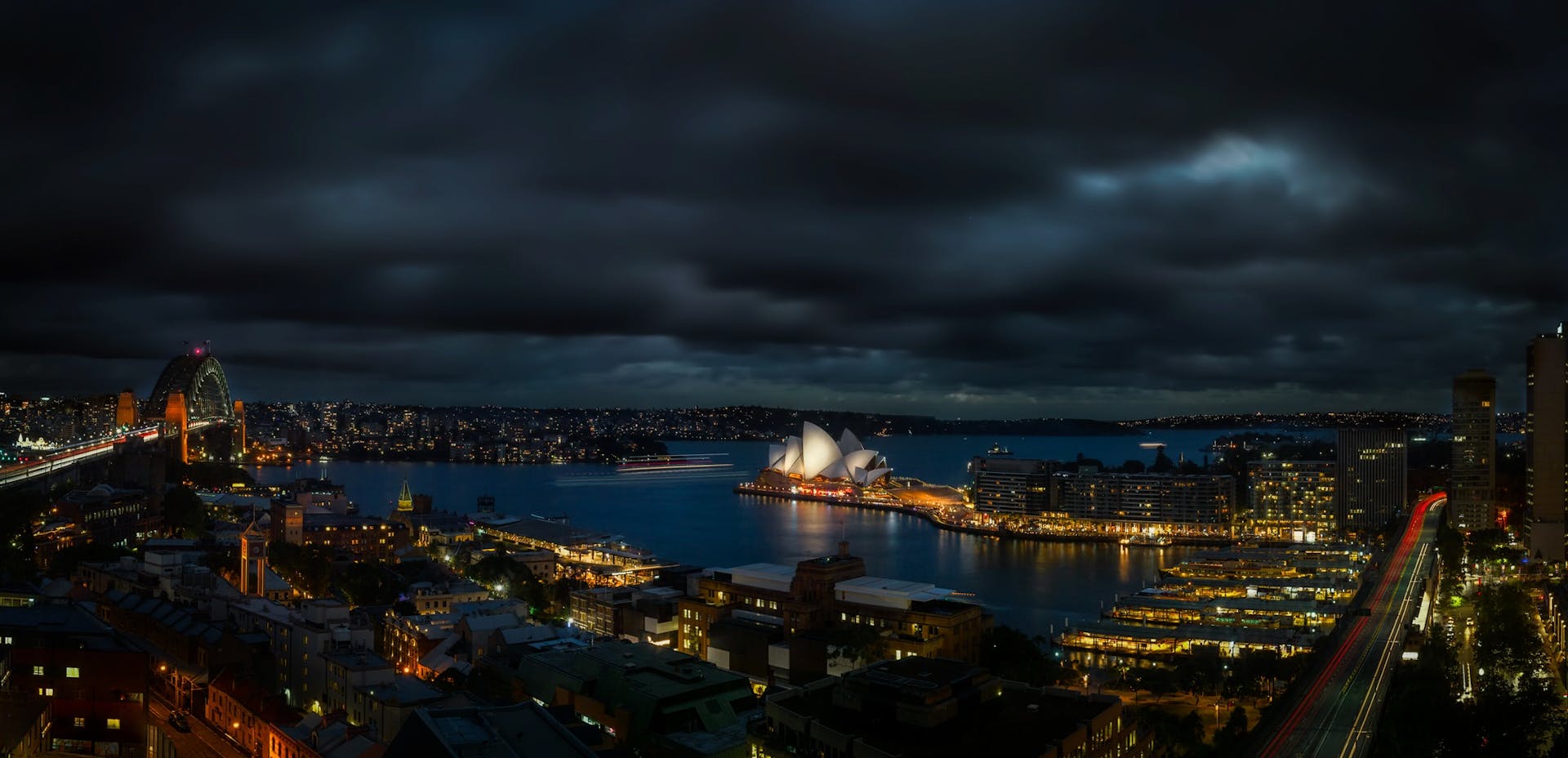 A breathtaking night view of Sydney Harbour with the Opera House and cityscape lights.