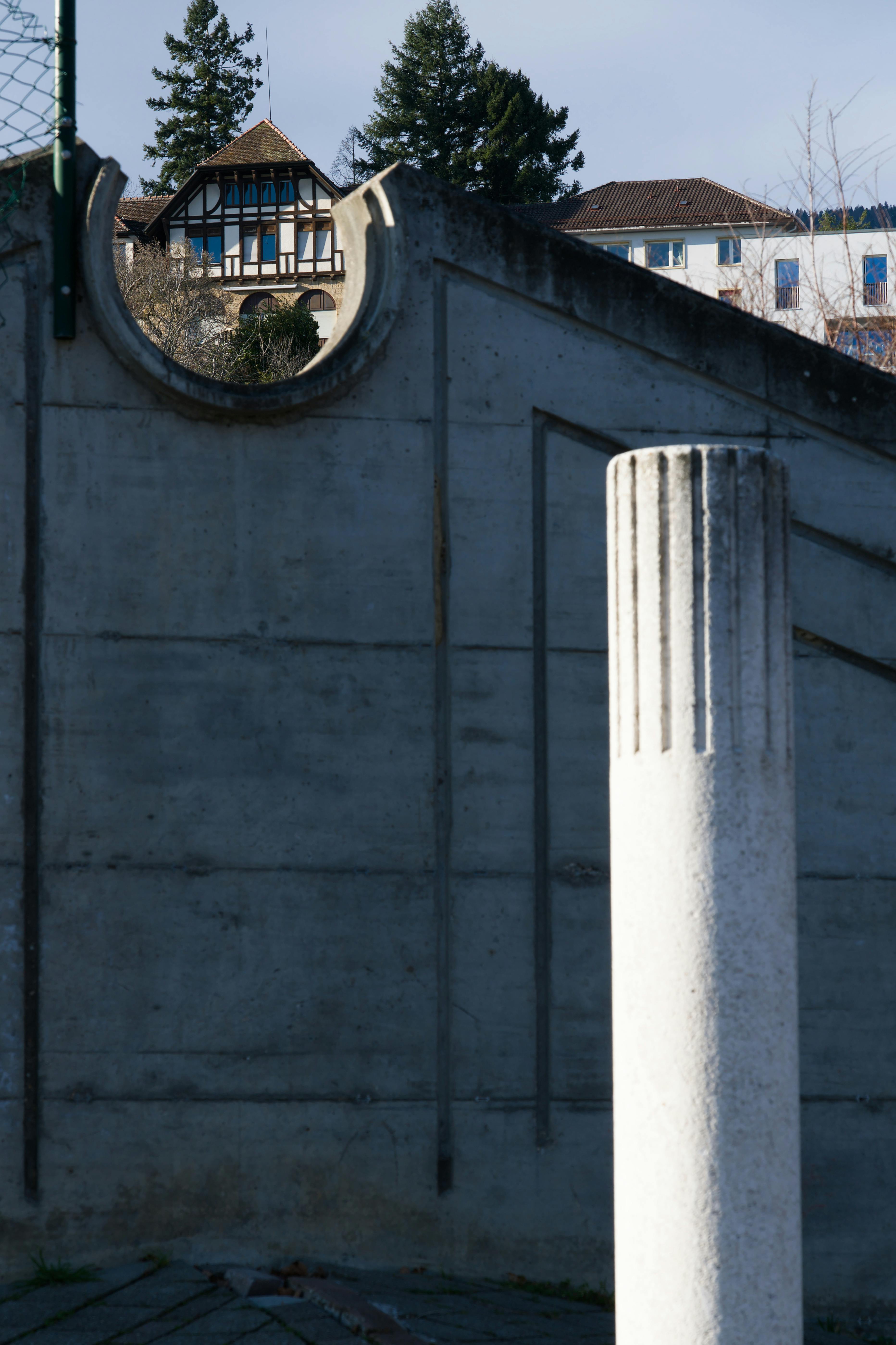 Gratuit Un pilier en béton devant une maison de style Tudor reflète le contraste architectural. Photos