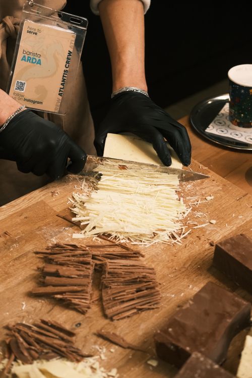 Free Barista expertly shaves white chocolate at a café, showcasing gourmet preparation. Stock Photo