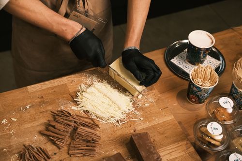 Free Barista skillfully preparing gourmet hot chocolate with white and dark chocolate shavings. Stock Photo