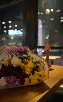 A vibrant bouquet of flowers sits on a cafe table with a warm atmosphere.