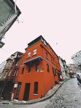 Vibrant red building on a steep, cobblestone urban street showcasing unique architecture.