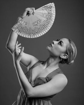 Artistic black and white portrait of a woman posing gracefully with a decorative fan.