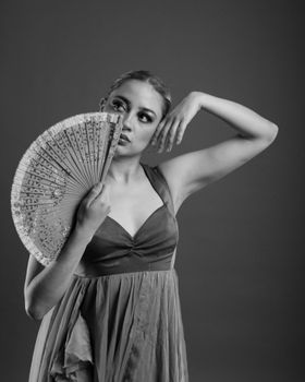 Artistic black and white portrait of a woman with a fan, exuding grace and elegance.