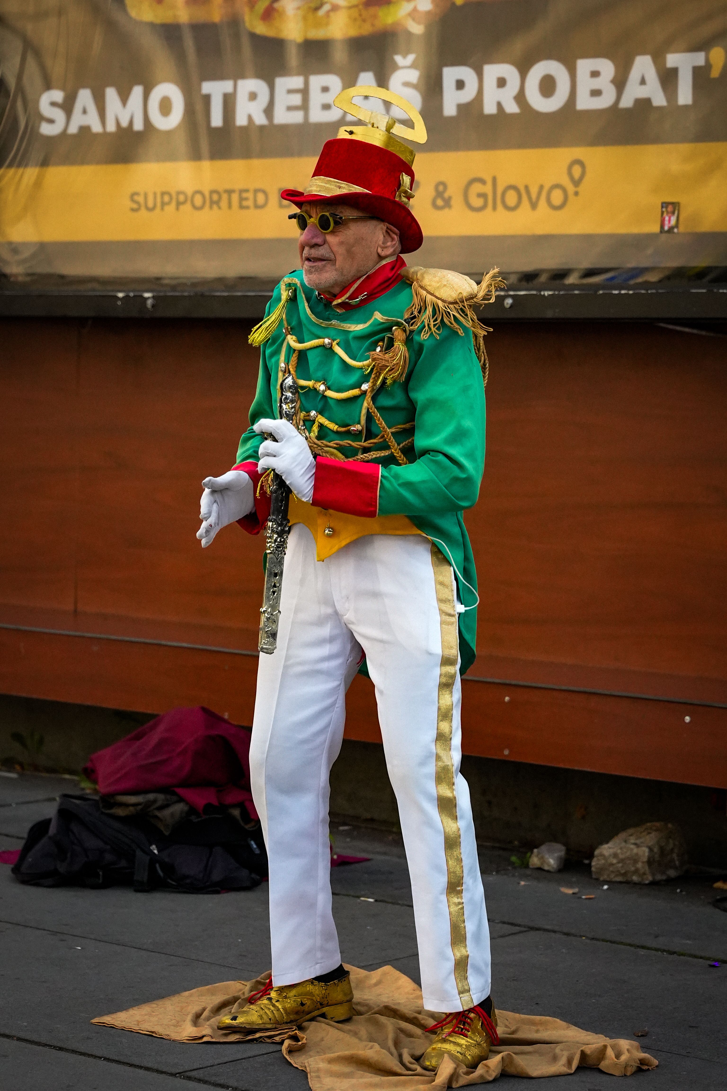 Elderly street performer in vibrant costume playing musical instrument, Sarajevo.
