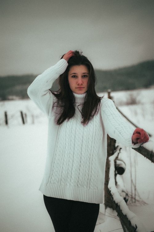 Free A young woman in a cozy sweater stands outdoors in a snowy Ukrainian landscape, exuding a warm, moody vibe. Stock Photo