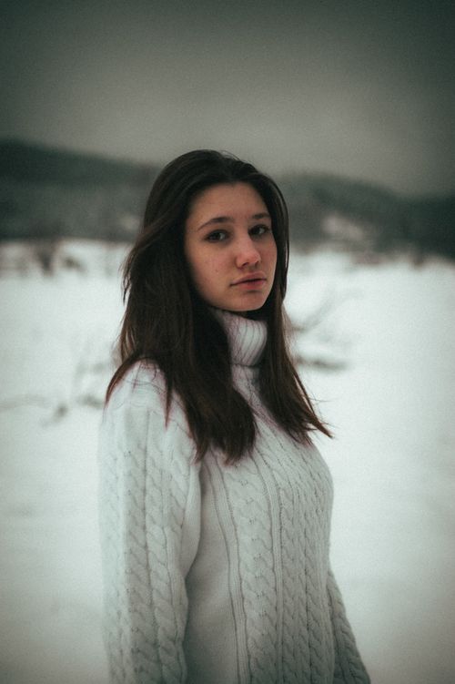 Free A moody winter portrait of a woman in a cozy sweater amidst snowy landscapes in Ukraine. Stock Photo