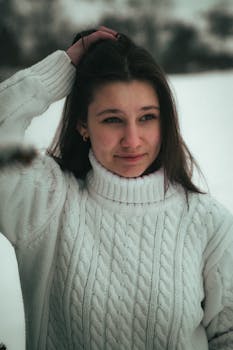 A woman in a cozy sweater enjoying the winter snow in Ukraine's serene outdoors.