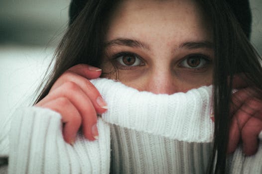 A young woman in a cozy sweater enjoys the winter outdoors in Ukraine, capturing a moody and aesthetic moment.