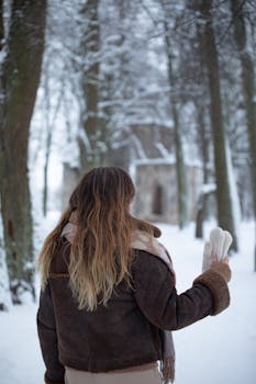 Woman with long hair walking in a snowy forest, enjoying a serene winter day.