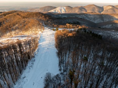 A picturesque aerial view of snowy mountains and forests in Daruvar, Croatia during sunset.