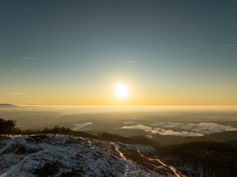 Stunning sunset view over snow-covered hills near Daruvar, Croatia, with a warm, serene sky.