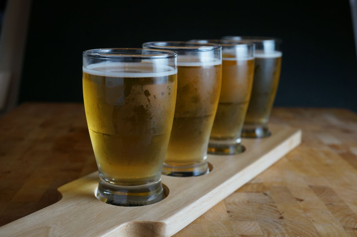 A flight of beer on a wooden tasting paddle